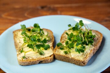 Fototapeta na wymiar Set sandwiches for breakfast. Sandwiches with micro greens on blue plate on wooden background, tasty and fresh organic food healthy breakfast snack concept