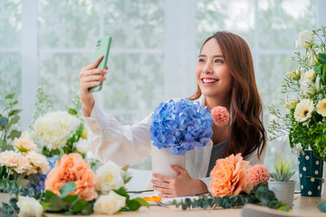Small business. Asia Female florist smile arranging flowers in floral shop. Flower design store. happiness smiling young lady taking photo of her vase to social media publish internet marketing ideas