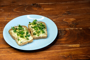 Set sandwiches for breakfast. Sandwiches with micro greens on blue plate on wooden background, tasty and fresh organic food healthy breakfast snack concept