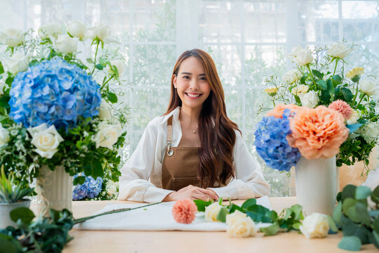 portrait Asia Female florist smile arranging flowers in floral shop. Flower design store. happiness smiling young lady making flower vase for customers, preparing flower work from home business