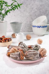 Assorted dried fruits on a white table. Dried persimmons, walnuts and dates next to the kitchen utensils. Eco dried fruits