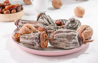 Assorted dried fruits on a white table. Dried persimmons, walnuts and dates next to the kitchen utensils. Eco dried fruits