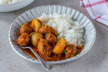 Sausage meatballs and potatoes in curry sauce with rice