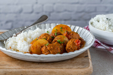 Sausage meatballs and potatoes in curry sauce with rice