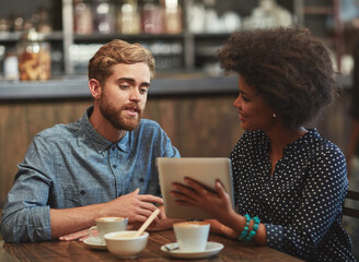 Discussing new ideas for their coffee shop. Shot of a young couple using a digital tablet together on a coffee date.