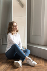 Young blond beautiful girl is sitting on wooden floor