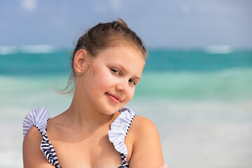 Pretty little girl in swimsuit stands on beach