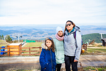 Portrait of a happy family at the top with a view of mountain landscape on the autumn day. Mother with daughters in nature.