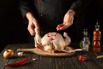 Cooking chicken in the kitchen with the hands of a chef. Before baking, the cook adds red viburnum to raw chicken. European cuisine