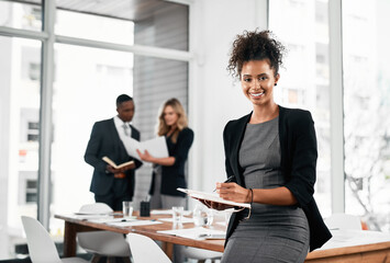 Connectivity keeps me at the fore of success. Portrait of a young businesswoman using a digital tablet in an office with her colleagues in the background.