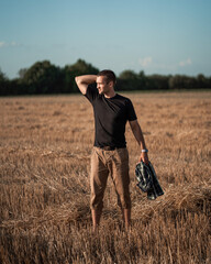 handsome man with short bristles in a black T-shirt in a beveled field