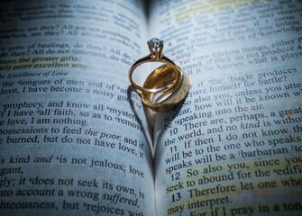Gold Wedding Rings in the Center of the Bible Forming a Heart with the Shadow
