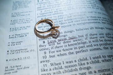 Woman's Gold Wedding Ring on a Bible with the Scripture Love Never Fails