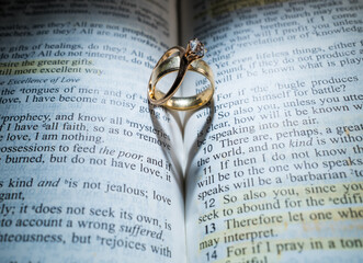 Gold Wedding Rings in the Center of the Bible Forming a Heart with the Shadow