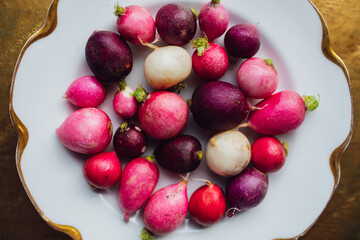 trimmed pink, red, purple, white radishes on white plate with gold, root vegetables, spring