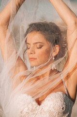Close-up portrait of a brunette model girl in the role of a bride. Beautiful face, portrait at sunset in summer day.