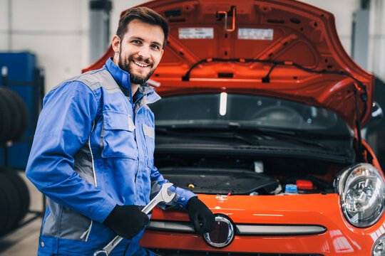 Young good looking professional mechanic working in a car service.