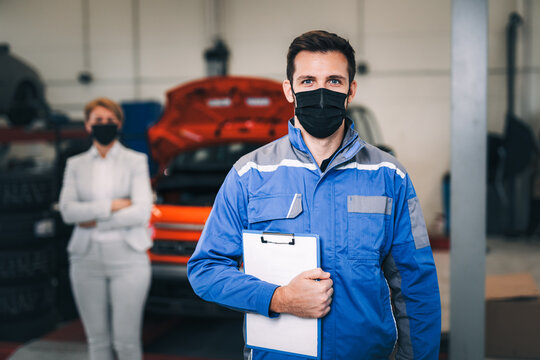 Portrait of mechanic with protective face mask working in car repair service.