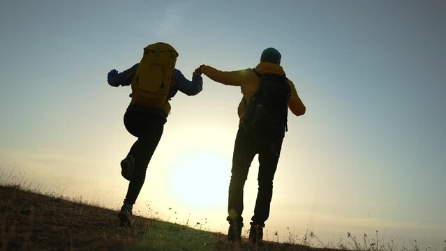business teamwork a freedom concept. couple of tourists run with silhouette backpacks running jumping. travel freedom business concept. couple teamwork hikers sunset running jumping