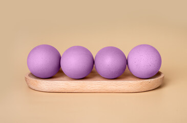 Purple dyed Easter eggs at wooden server on beige background. Preparation to religious holiday celebration concept in minimalism style. High quality photo