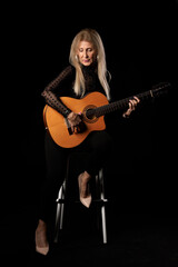 Fototapeta na wymiar blonde woman with guitar in studio on black background