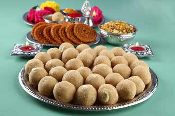 diwali festival snacks chakali or chakli, rava besan laddu with puja thali or puja plate