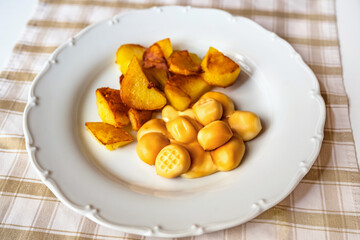 Smoked cheese balls with fried potato on plate on table.