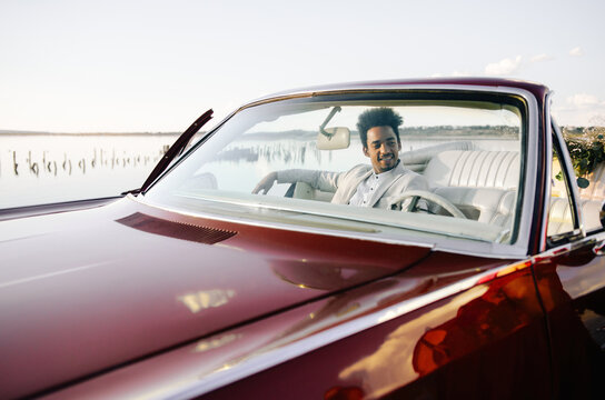 Handsome african american man in light suit on bright red cabriolet