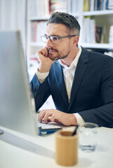 He has a keen eye for detail. Shot of a mature businessman working at his computer in an office.