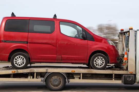 Red passenger minibus is transported by tow truck. Car evacuation, transfer, delivery to a car service. Motion blur