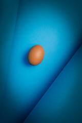 Jajko na błękitnym tle z delikatnym światłem.