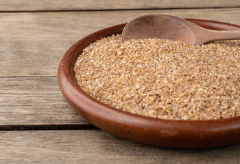 Ground whole wheat on a plate over wooden table with short depth of field