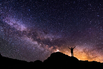 Obraz premium Silhouette of a hiker on the hill in starry night sky. Bright milky way galaxy behind him.