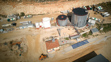 Structures of plant producing sand, crushed stone, cement and batching concrete and asphalt. Mixer trucks, concrete pumping machines, gas tanks and silos aerial view. Construction materials production © Philipp Berezhnoy