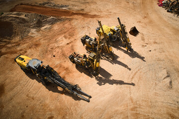 Yellow drilling rigs using to drill holes during blasthole drilling operations parked on dirt...
