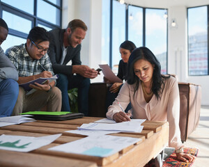 Working those creative minds. Shot of a team of creative colleagues making notes during a meeting in their office.