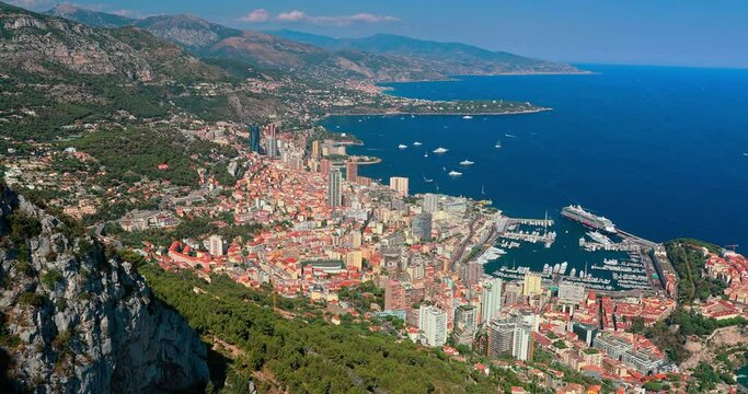 Aerial view of principality of Monaco at sunset, Monte-Carlo, luxury buildings, soccer stadium, view of city life from La Turbie mountain, a lot of mega yachts and boats, water horizon 