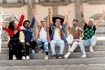 Multiracial group of happy young friends laughing together and having fun sitting near the...