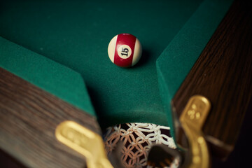 billiard ball near the hole. Pool ball lucky number 15 near hole on green billiard table.