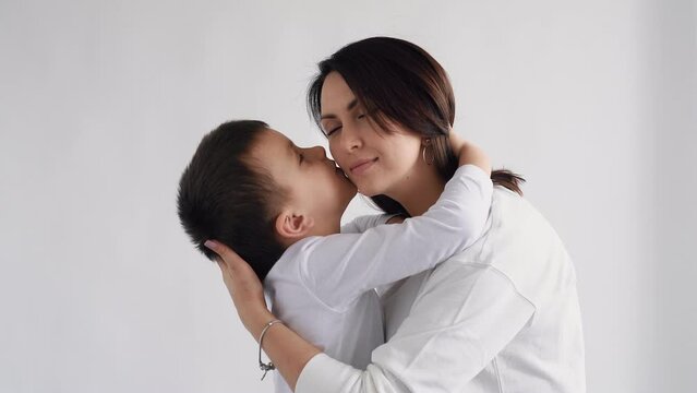 Loving tender young mum holding adorable cute baby girl daughter embracing kissing small kid. Happy affectionate mixed race mother cuddling with infant child boy son standing at home.