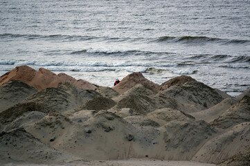 Zwały piasku na plaży na budowie przekopu budowlaniec w kasku