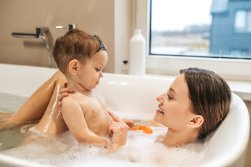 Smiling woman taking a bath with her baby
