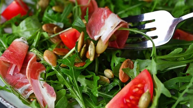 Eating salad. Healthy italian salad with tomatoes, arugala and hamon. Fresh salad with hamon. Green salad with prosciutto.