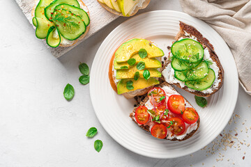 Bruschetta with feta, tomato, avocado and cucumber, on a gray background.