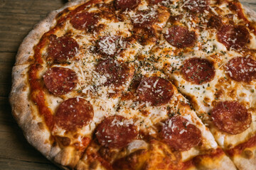 Delicious hot meat pizza with prosciutto and salami on a wooden table. High quality photo
