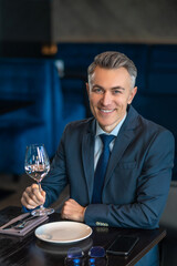 An elegant man trying white wine and looking contented