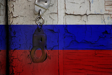 Handcuffs hang on an old cracked door against the background of the Russian flag, stop the war in...