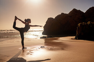 Yoga will change your life for the better. Shot of a young woman practicing yoga at the beach.