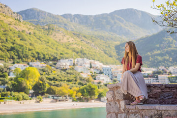 Fototapeta na wymiar Woman tourist on background of beautiful view of the island of St. Stephen, Sveti Stefan on the Budva Riviera, Budva, Montenegro. Travel to Montenegro concept