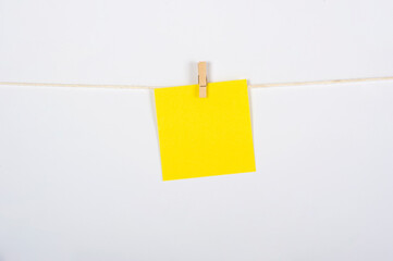 Postik amarillo colgado con pinza sobre fondo blanco para concepto ejercicio, recordatorio o mensaje.